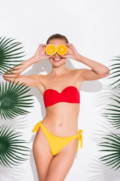 Mulher Feliz Maiô Sorrindo Enquanto Cobre Olhos Com Metades Laranja — Fotografia de Stock