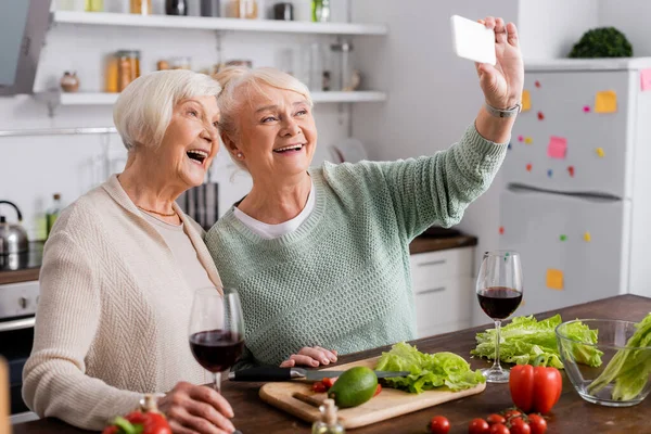 Neşeli Son Sınıf Öğrencisi Kadın Emekli Arkadaşıyla Mutfakta Selfie Çekiyor — Stok fotoğraf
