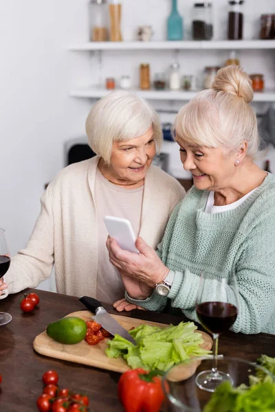 Happy Senior Woman Holding Smartphone Retired Friend Kitchen — Stock Photo, Image