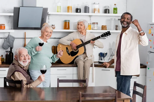 Mujer Jubilada Feliz Tocando Guitarra Acústica Cerca Amigos Mayores Multiculturales — Foto de Stock