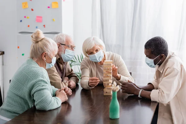 Retired Multicultural Friends Medical Masks Playing Tower Wood Blocks Game — Stock Photo, Image