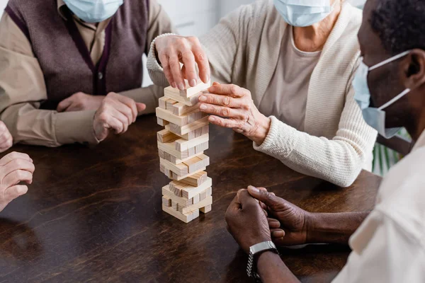 Pensionistas Multiculturales Máscaras Médicas Jugando Bloques Madera Torre Juego Casa — Foto de Stock