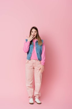 Harika bir genç pembe arka planda kameraya bakıyor.