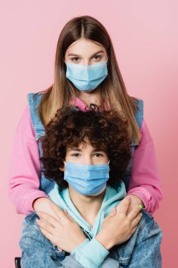 Girl in medical mask holding hands of boyfriend isolated on pink  clipart