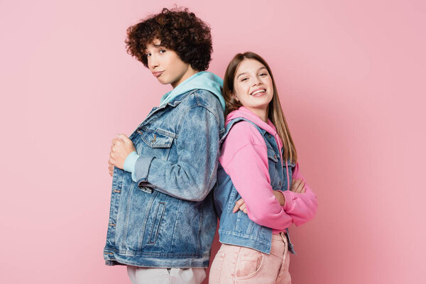 Teenagers in casual clothes looking at camera on pink background