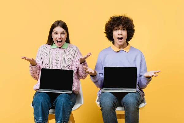 Amazed Teenagers Holding Laptops Chairs Yellow Background — Stock Photo, Image