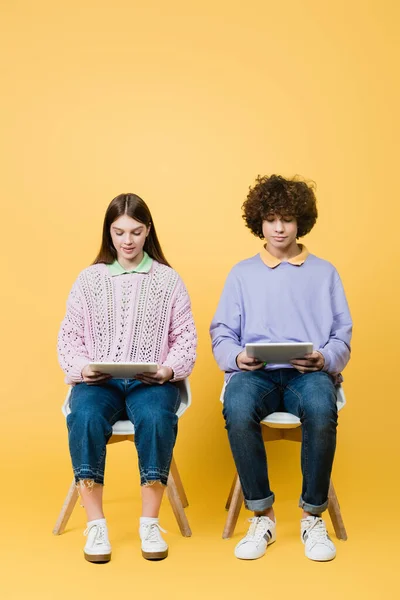 Teen Friends Using Digital Tablets Chairs Yellow Background — Stock Photo, Image