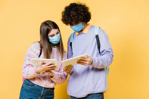 Teen Friends Medical Masks Backpacks Using Digital Tablets Yellow Background — Stock Photo, Image