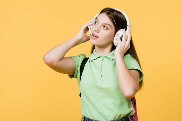 Teenager using headphones isolated on yellow