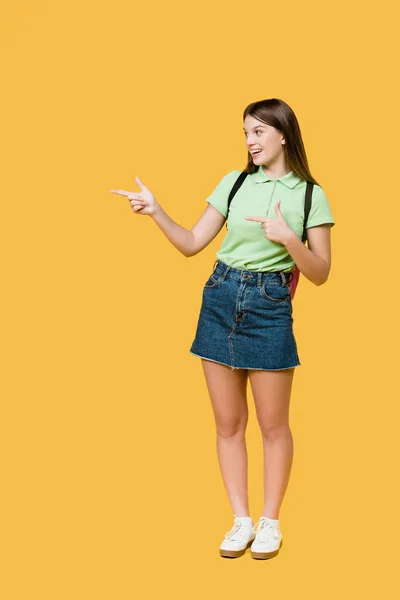 Adolescente Sonriente Con Mochila Apuntando Con Los Dedos Aislados Amarillo —  Fotos de Stock