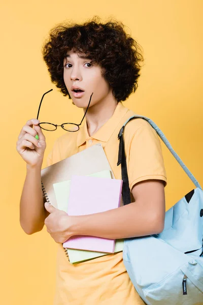 Emocionado Adolescente Con Anteojos Cuadernos Mochila Mirando Cámara Aislada Amarillo —  Fotos de Stock