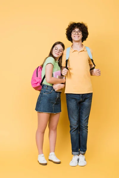 Usmívající Teenager Batohem Stojící Poblíž Přítele Notebooky Žlutém Pozadí — Stock fotografie