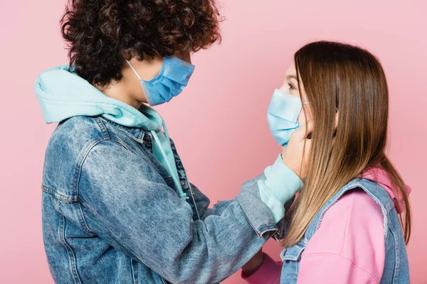 Nastolatki Maskach Medycznych Patrząc Siebie Odizolowane Różowo — Zdjęcie stockowe