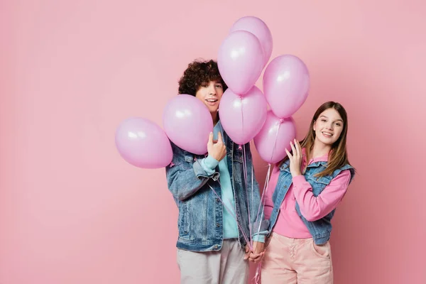 Sonriente Pareja Adolescente Cogida Mano Cerca Globos Rosados Sobre Fondo —  Fotos de Stock