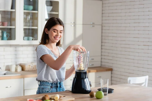 Mujer Feliz Añadiendo Plátano Licuadora Mientras Prepara Desayuno Cocina — Foto de Stock