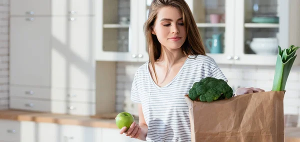 Joven Mujer Sosteniendo Manzana Madura Cerca Bolsa Papel Con Puerro —  Fotos de Stock