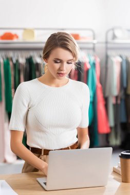 Sarışın satıcı, sergi salonuna gitmek için kahvenin yanındaki bilgisayarı kullanıyor. 