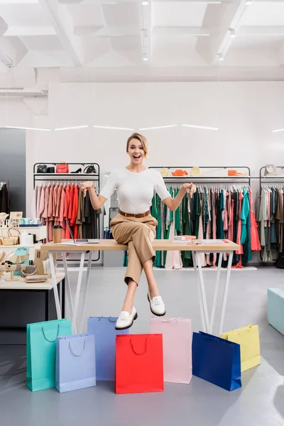 Cheerful Seller Pointing Shopping Bags Showroom — Stock Photo, Image