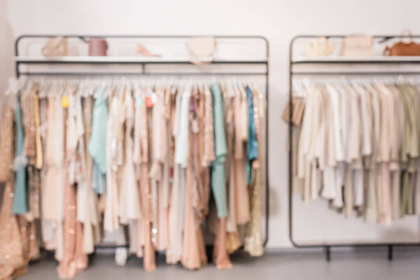 Blurred background of clothes on hanger racks in showroom 