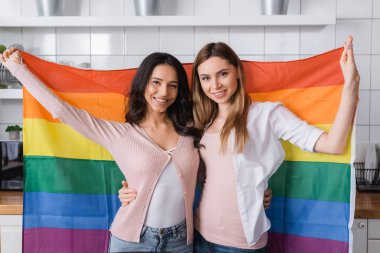 cheerful lesbian couple holding lgbt flag 