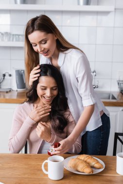 happy woman holding jewelry box with wedding ring near amazed girlfriend