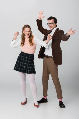 Gri renkte dans eden, eski moda elbiseli heyecanlı çiftin tam boy görüntüsü.