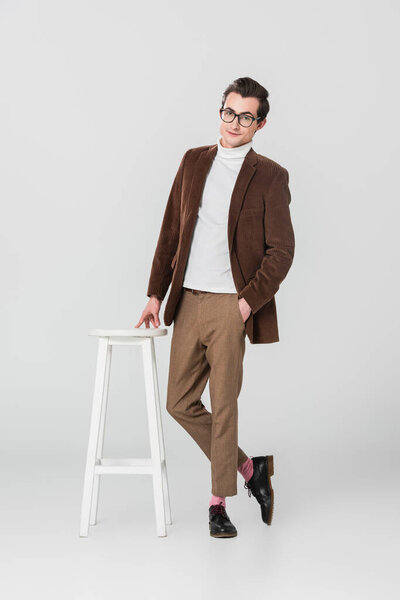 full length view of retro style man posing near high chair on grey background