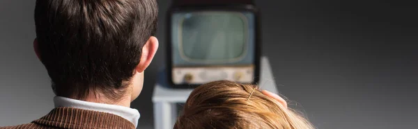 一对夫妇在灰色背景 横幅上观看复古电视的背景图 — 图库照片