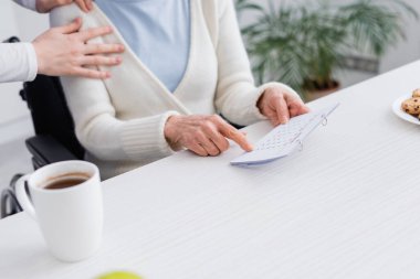 cropped view of nurse touching shoulder of senior woman pointing at calendar while suffering from memory loss clipart