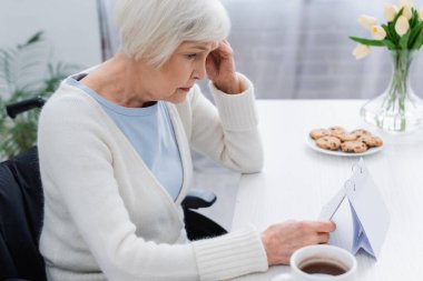 senior woman, suffering from memory loss, looking at calendar at home clipart