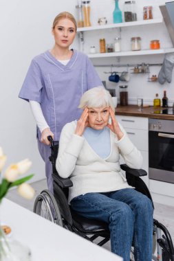 young nurse looking at camera near disabled elderly woman sick on dementia clipart