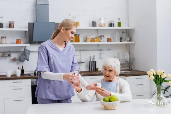 Enfermera Joven Dando Vaso Agua Medicamentos Mujer Mayor Cocina —  Fotos de Stock