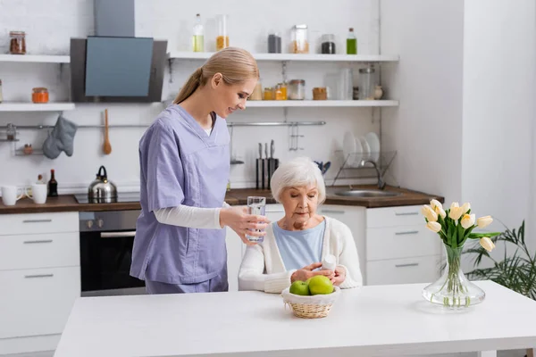 Jeune Infirmière Donnant Verre Eau Une Femme Âgée Tenant Récipient — Photo