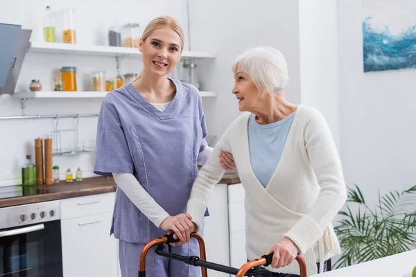 Young Nurse Smiling Camera While Supporting Aged Woman Medical Walkers — Stock Photo, Image