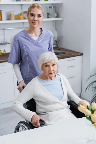 Young Nurse Senior Disabled Woman Looking Camera Kitchen — Stock Photo, Image