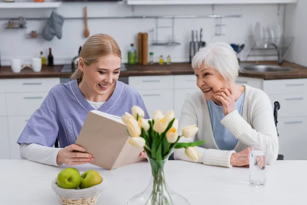 Lächelnde Krankenschwester Liest Fröhlicher Seniorin Der Küche Bei Frischen Äpfeln — Stockfoto