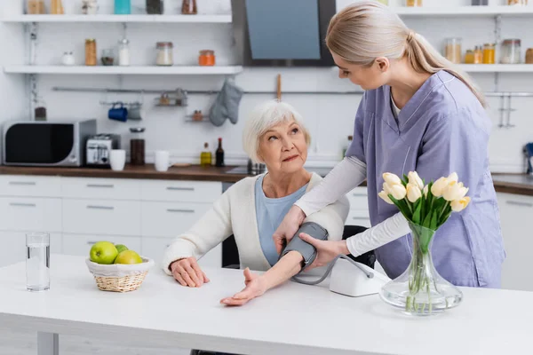 Jonge Verpleegster Oudere Vrouw Kijken Elkaar Aan Terwijl Bloeddruk Keuken — Stockfoto