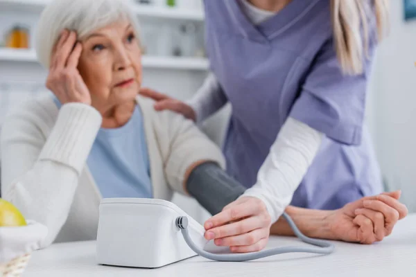 Femeie Vârstă Atingând Capul Timp Asistenta Medicală Măsurând Tensiunea Arterială — Fotografie, imagine de stoc
