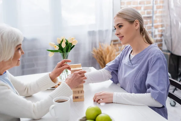 Giovane Assistente Sociale Donna Anziana Giocare Blocchi Legno Gioco Casa — Foto Stock