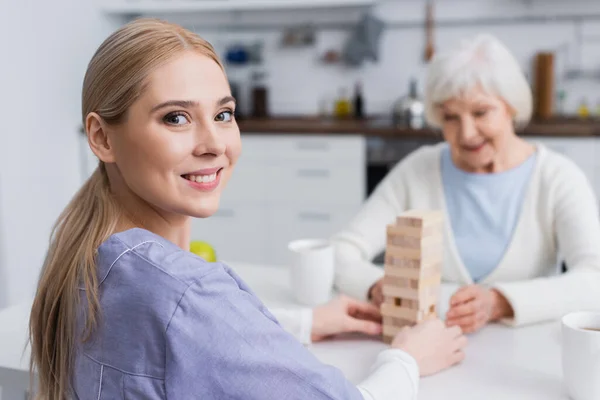 Enfermera Feliz Mirando Cámara Mientras Juega Juego Torre Madera Con — Foto de Stock