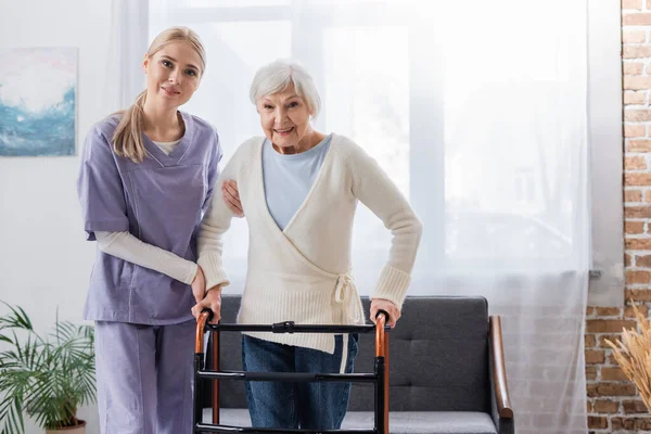 Happy Nurse Senior Woman Looking Camera Medical Walkers Living Room — Stock Photo, Image