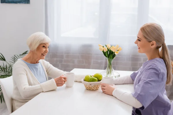 Gioiosa Donna Anziana Giovane Assistente Sociale Che Parla Cucina Vicino — Foto Stock