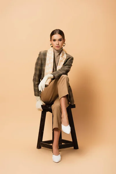 Elegante Donna Pantaloni Blazer Scarpe Bianche Guanti Seduta Sfondo Beige — Foto Stock