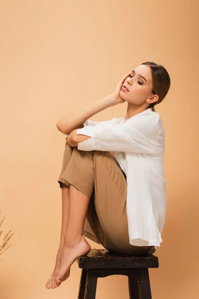 Mulher Descalça Segurando Mão Perto Rosto Enquanto Sentado Banquinho Madeira — Fotografia de Stock