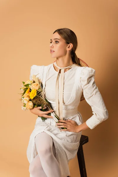 Jovem Mulher Vestido Branco Segurando Buquê Com Flores Posando Bege — Fotografia de Stock
