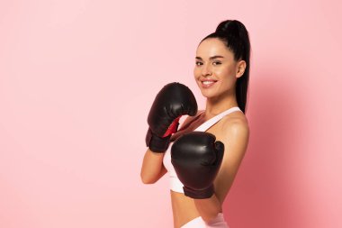 Spor giyimli neşeli kadın ve pembe eldivenli boks eldiveni. 
