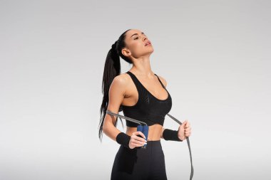 Genç ve yorgun sporcu kadın gri ipten atlıyor.