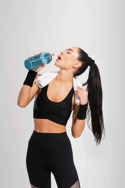 Ung Idrottskvinna Med Handduk Axlarna Dricksvatten Isolerad Grå — Stockfoto