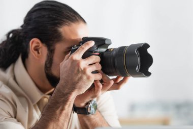 Bulanık Latin adam, modern dijital kamerada fotoğraf çekiyor.