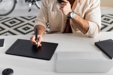 Masa başındaki dizüstü bilgisayarın yanındaki grafik tablet üzerinde kırpılmış rötuş görüntüsü